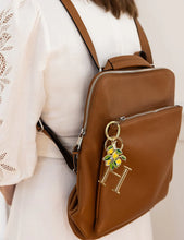 Load image into Gallery viewer, Brown leather backpack with a decorative keychain on a neutral background