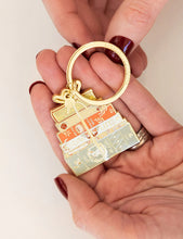 Load image into Gallery viewer, Gold keychain with decorative elements held in a hand against a white background