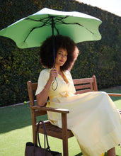 Load image into Gallery viewer, Woman sitting on a chair holding a green umbrella in an outdoor setting