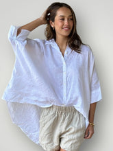 Load image into Gallery viewer, Woman wearing a white oversized shirt and beige shorts against a plain background